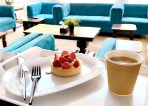 un plato con un pastel en una mesa con una taza de café en اريس الشرق للشقق المخدومة en Yeda