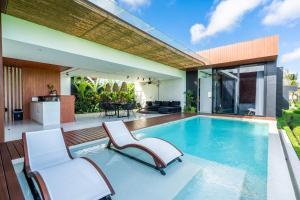 an indoor swimming pool with two chairs and a house at GREEN FLOW Villas Ubud I in Ubud