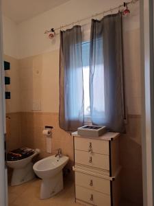 フィウミチーノにあるARMAREAOVERSEASSUITESのバスルーム(洗面台、トイレ付)、窓が備わります。