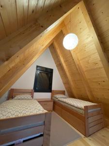 2 Betten in einem Dachzimmer mit einem TV in der Unterkunft KoCHALET Apartment in Crni Vrh