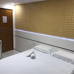 a white bed with two pillows in a room at Goiana Palace Hotel - Fácil Acesso a Fábrica da JEEP in Goiana