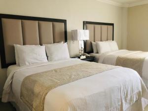 Habitación de hotel con 2 camas con sábanas blancas en Hotel Quinta Real, en La Ceiba