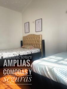 um quarto com duas camas e duas fotografias na parede em A 5 minutos del Aeropuerto el Dorado em Bogotá