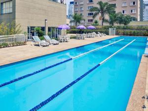 a swimming pool with blue water and chairs and umbrellas at Mercure São Paulo vila Olimpia premium in Sao Paulo