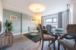 a dining room and living room with a glass table at Victoria Brand new, cosy 1 bed apartment in London