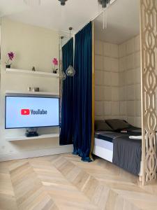 a bedroom with a television and a bed with blue curtains at Cozy Apartment on Piotrkowska Street in Łódź