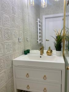 uma casa de banho com um lavatório branco e um espelho. em Cozy Apartment on Piotrkowska Street em Lódź