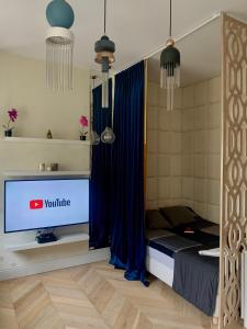um quarto com uma televisão e uma cama com cortinas azuis em Cozy Apartment on Piotrkowska Street em Lódź