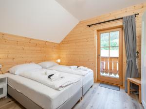 - une chambre avec un grand lit blanc et une fenêtre dans l'établissement Wolfgangchalet B, à Mauterndorf