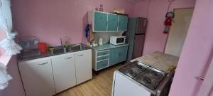 una pequeña cocina con paredes rosas y armarios blancos. en Casavistacolliguay, 