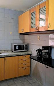 a kitchen with wooden cabinets and a microwave on a counter at Apartamento IdeaL Independencia VI in Mendoza