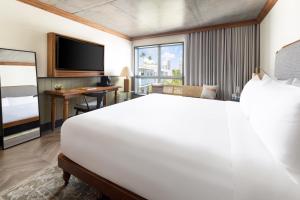 una camera d'albergo con un grande letto bianco e una scrivania di The Balfour Hotel a Miami Beach