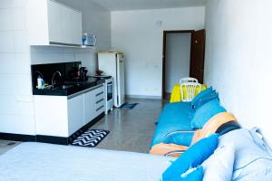 a living room with a blue couch and a kitchen at Otimo studio c WiFi no centro de Pedro Leopoldo MG in Pedro Leopoldo