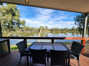 a table and chairs on a deck with a view of a lake at Rivergardens Holiday Park Mildura in Gol Gol