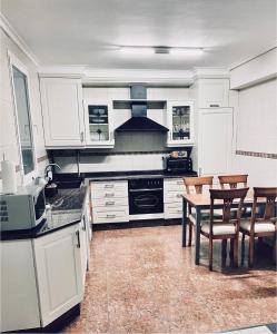 a kitchen with white cabinets and a table and chairs at Apartamento Logroño in Logroño