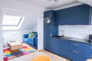 a kitchen with blue cabinets and a blue couch at Le Champs-Elysees - Cité universitaire Paris 14 in Gentilly