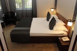 a bedroom with a bed with white sheets and black pillows at Lévay Villa Hotel in Miskolc