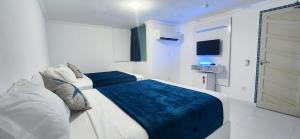 um quarto branco com 2 camas e uma televisão em Zenith em Arraial do Cabo