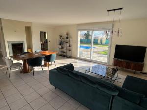a living room with a couch and a table and a tv at Villa ski proche de Genève et du Jura in Saint-Genis-Pouilly