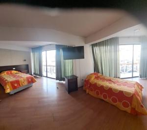 Hotel Charlie Inn في إكيكي: غرفة نوم بسريرين وتلفزيون بشاشة مسطحة
