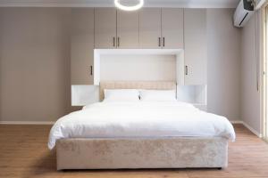 een slaapkamer met een groot wit bed met een groot hoofdeinde bij Trio Apartment's City Center Tirana in Tirana