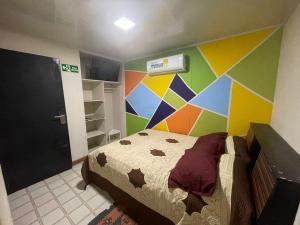 1 dormitorio con una pared colorida y 1 cama en Donde missluz inn en San Andrés