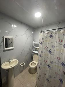 y baño con aseo, lavamanos y cortina de ducha. en Donde missluz inn en San Andrés