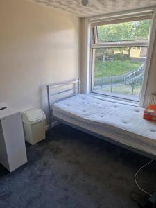 um pequeno quarto com uma cama e uma janela em Cozy Bedroom in Spacious House Manchester em Rochdale