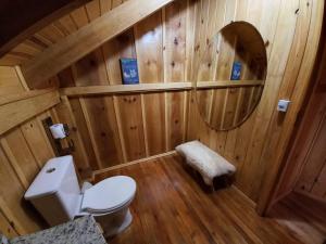 ein Bad mit einem WC und einem runden Spiegel in der Unterkunft Chalés Sol da Serra in Rio Rufino