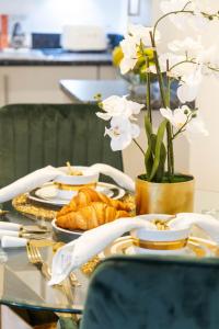 une table avec un plateau de croissants et de fleurs blanches dans l'établissement Preciousluxurysuit, à Bromley