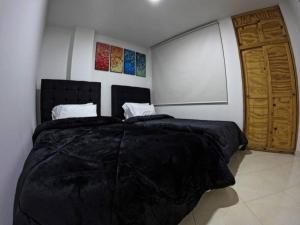 a bedroom with a large bed and a wooden door at Luminoso y Confortable apt 6 minutos del aeropuerto in Bogotá