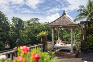 a woman sitting on a bed in a gazebo at Kawi Resort A Pramana Experience in Tegalalang