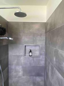 La salle de bains est pourvue d'une douche et d'une bouteille de savon. dans l'établissement Charming Mid Century Bungalow, à Stanthorpe