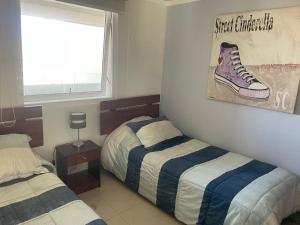 1 dormitorio con 2 camas y una pintura de un zapato en la pared en Moderno departamento acceso a playa, en Coquimbo