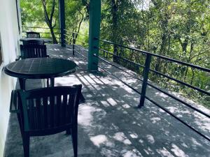 a patio with two chairs and a table on a balcony at Forest Villa in Sigiriya