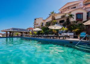 a swimming pool at a resort with tables and umbrellas at Marina View Villas in Cabo San Lucas