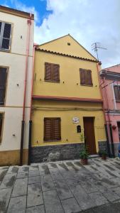 a yellow building with brown shutters on it at Casa vacanze Galena in Iglesias