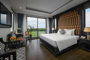a bedroom with a white bed and a large window at Serene Nature Hotel & Spa in Hoi An