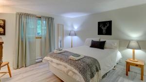 1 dormitorio con cama blanca y ventana en Chalet dans les arbres. 3 ch. /trees house 3bdr, en Lac Sainte-Marie