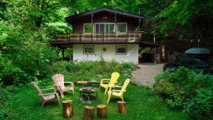 um grupo de cadeiras sentadas na relva em frente a uma casa em Chalet dans les arbres. 3 ch. /trees house 3bdr em Lac Sainte-Marie