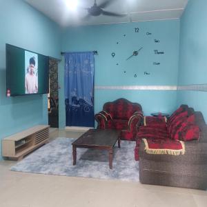 een woonkamer met 2 banken en een tv bij Nur Aisyah homestay kemaman..3 bedrooms in Kampong Kemaman