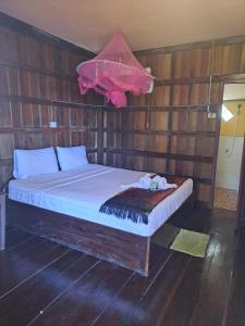 a bedroom with a bed in a wooden wall at Riverside Bungalow Don Det in Don Det