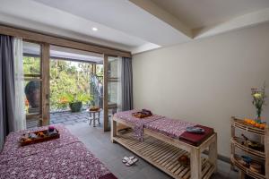 a bedroom with two beds and a sliding glass door at Kawi Resort Ubud in Tegalalang