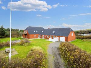 a red building with a black roof on a green field at Luxury Retreat by the Sea - By Traum Ferienwohnungen in Ulfborg