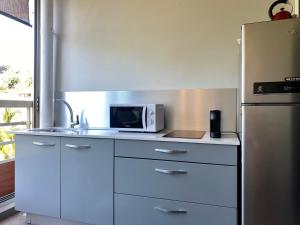 a kitchen with a microwave and a refrigerator at Iaorana Tahiti in Arue