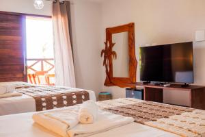 a hotel room with two beds and a flat screen tv at POUSADA E RESTAURANTE GAROUPA in São Miguel dos Milagres