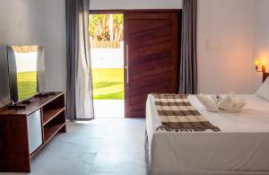 a bedroom with a bed and a tv and a window at POUSADA E RESTAURANTE GAROUPA in São Miguel dos Milagres +78 photos