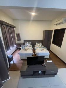 a room with two beds and a table with a laptop at Junikastay BLagoon Melaka in Malacca