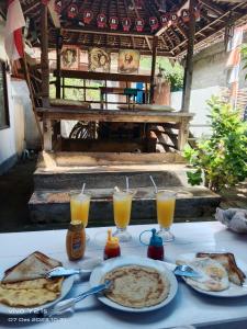 a table with plates of food and glasses of orange juice at fullesguesthouse in Gili Trawangan