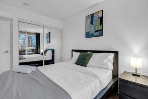 a white bedroom with a large bed and a window at Cityplace Luxury suites in Toronto